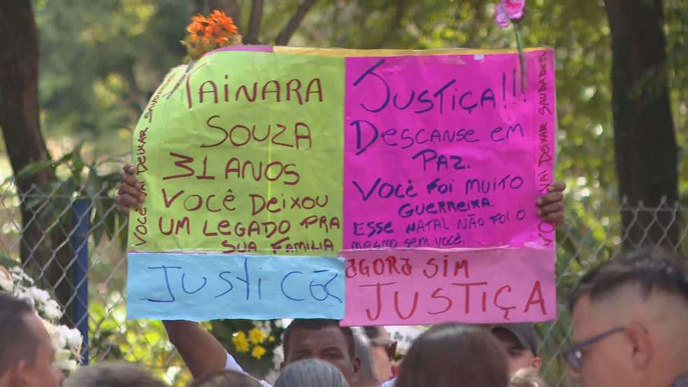 Image: https://thefolha.news/wp-content/uploads/2025/12/postiimg-694ec4a8d7acd1621.jpeg Cartaz pedindo justia no velrio de Tainara Souza Santos Foto Reproduo TV Globo